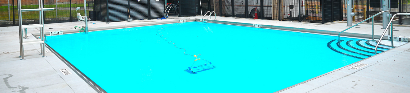 A small in-ground pool in a city playground. There are steps and a marker saying that the pool is three feet deep.