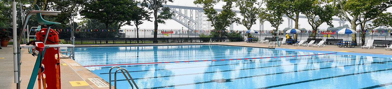 A city pool in front of a bridge.