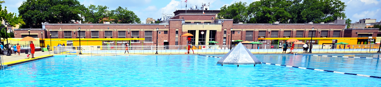 A massive outdoor pool and recreation center complex on a bright sunny day.