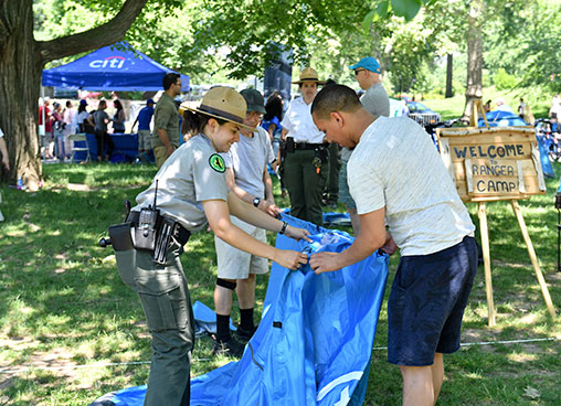 A park ranger shows a park guests how to set up a tent
