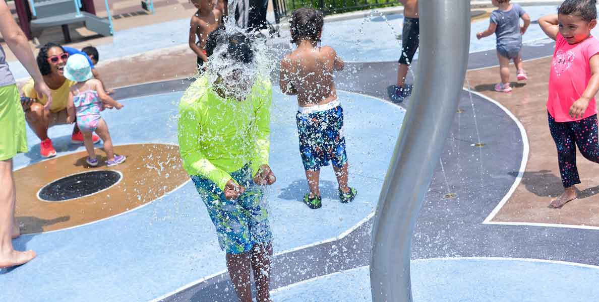 Child playing under water feature in a park