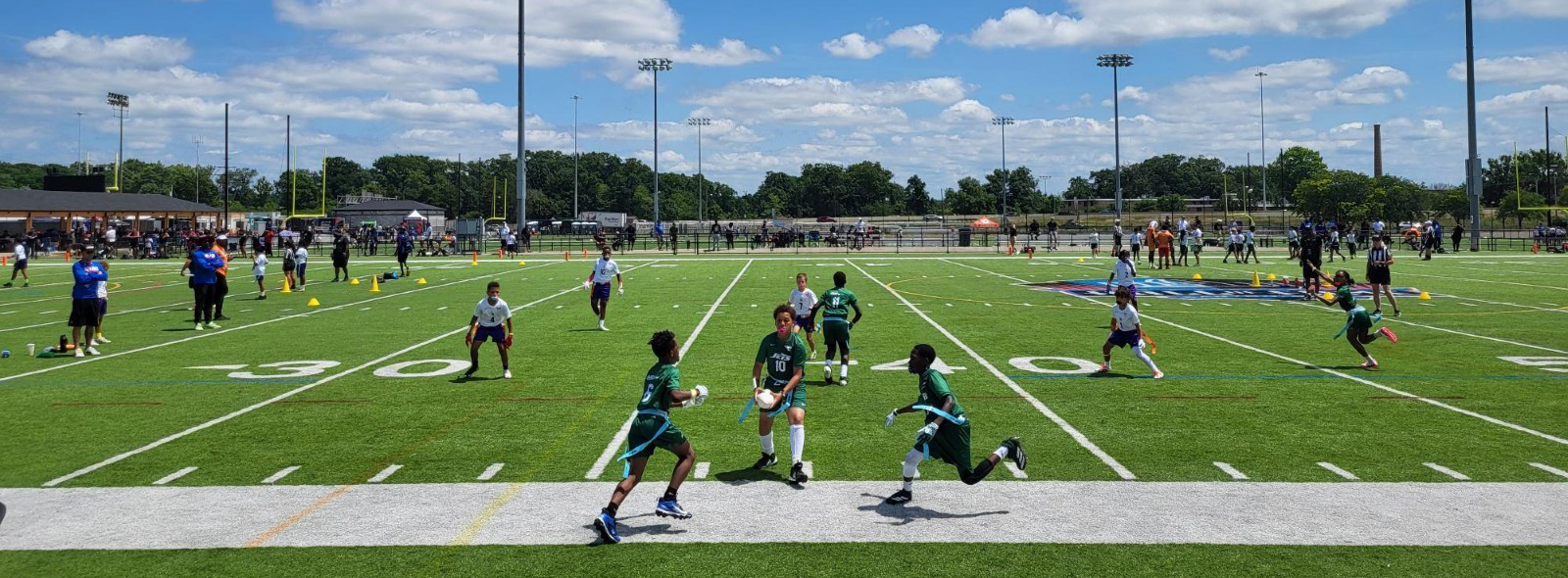 Kids play flag football on a football stadium field.