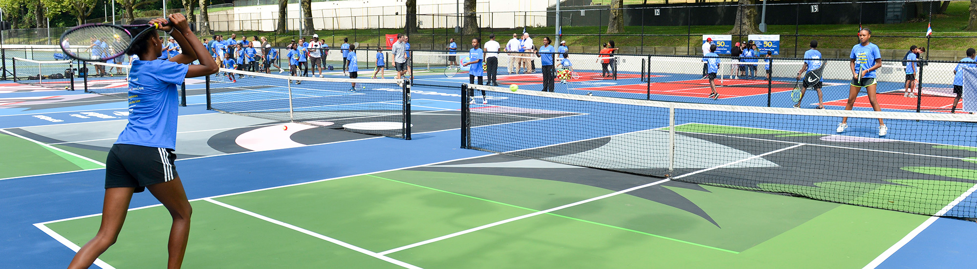 A teenager playing tennis on a colorfully painted tennis court.