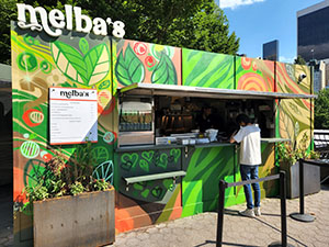 A painted and attractive food cart with a sign that reads "Melba's."