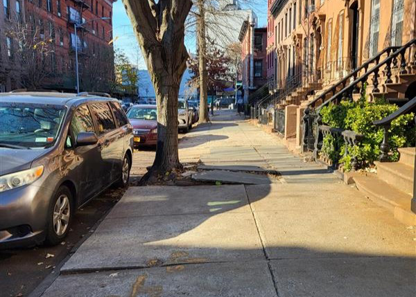 On this sidewalk, multiple flags have some lifting.