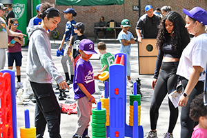 A group of children gather around a colorful, jumbo version of a table game.