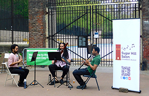 Three musicians sit in a circle and play their instruments.