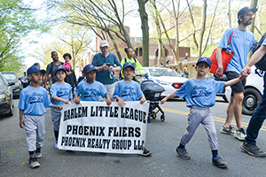 Five young boys in matching baseball uniforms hold a sign that says "Harlem Little League Phoenix Flyers Phoenix Realty Group LLC"