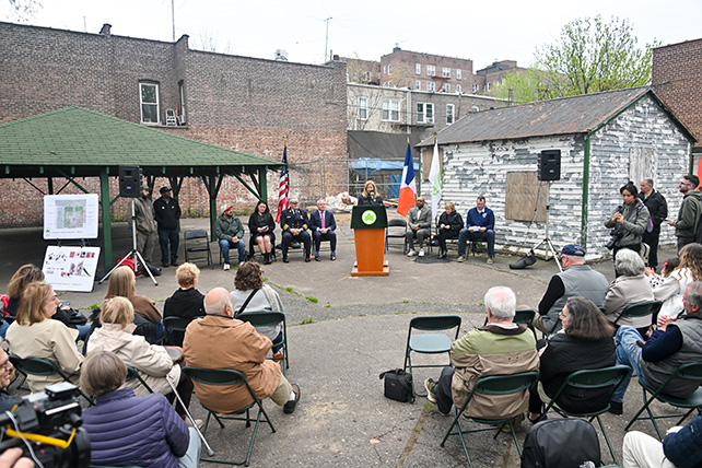 Former Parks Commissioner Sue Donoghue stands behind a podium, speaking to a seated crowd of community members