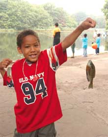 Proud fisherman in Macy’s Prospect Park Catch-and-Release fishing program Child holding up a fish caught in Prospect Park